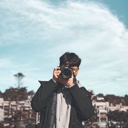 Portrait of man photographing against sky