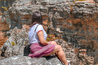 Side view of woman sitting on rock