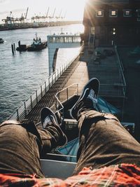 Low section of man relaxing by sea during sunny day