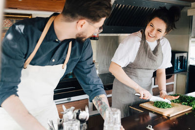 Smiling female entrepreneur cutting vegetable while working with male partner in commercial land vehicle