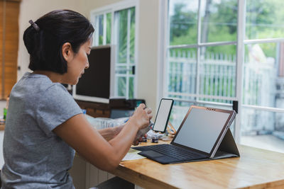 Asian woman marketing checking order online working on laptop computer at home.