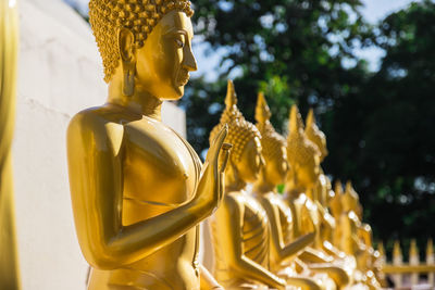 Golden buddha statues in row during sunny day