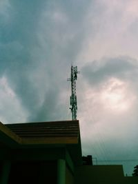 Low angle view of crane against cloudy sky