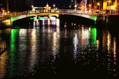 Illuminated bridge over river in city at night