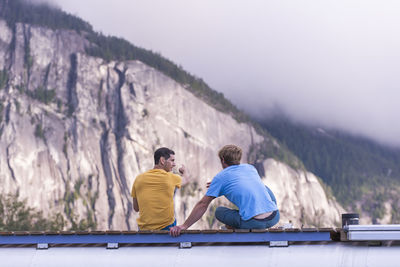 Man pointing out rock climbing cliff with finger on top of school bus