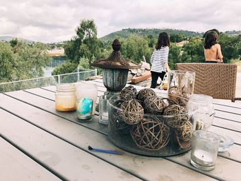 Rear view of people sitting on table against sky