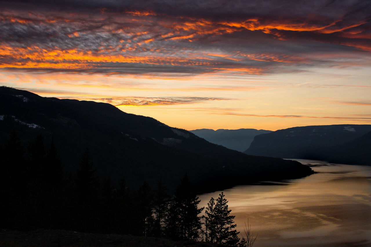 SCENIC VIEW OF SILHOUETTE MOUNTAINS AGAINST ORANGE SKY