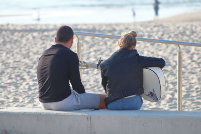 Woman playing guitar with friend at beach
