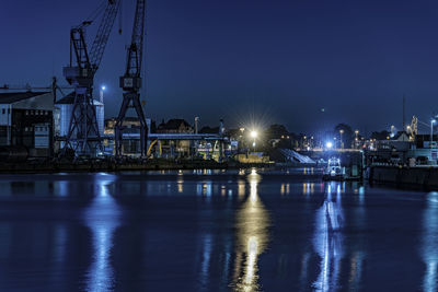 Illuminated harbor with water reflection by night