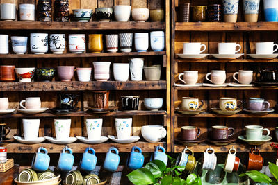 Small store with many pottery ceramic standing on shelves.