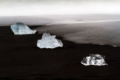 Close-up of ice on sea shore against sky