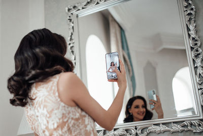 Smiling woman doing selfie through mirror