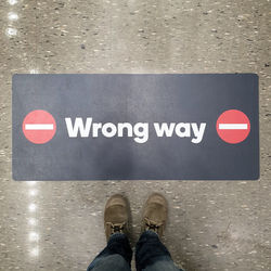 Low section of man standing on arrow sign