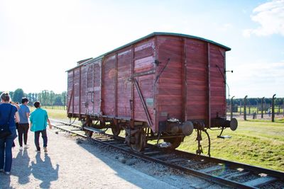 People walking by freight train on railroad track