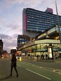 People walking on modern office building against sky