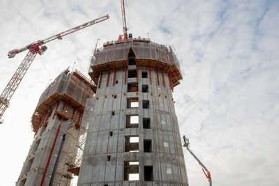 Low angle view of crane by building against sky