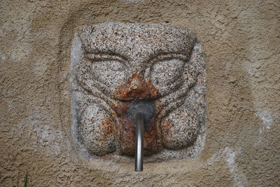 Close-up of old sculpture against wall