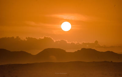 Scenic view of silhouette mountain against orange sky