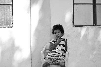 Portrait of young woman standing against window