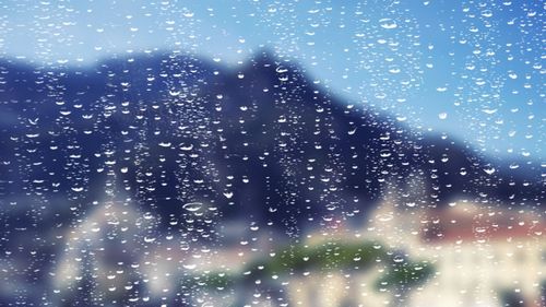 View of sky through wet window in rainy season
