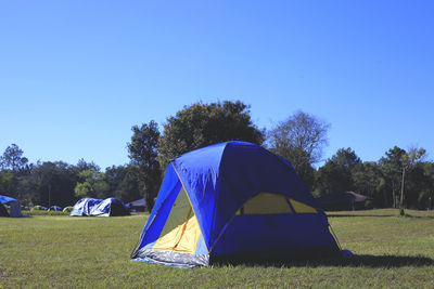 Tent in field against clear blue sky