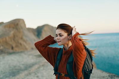 Young woman with arms raised against sky