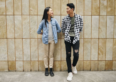 Young couple standing against wall