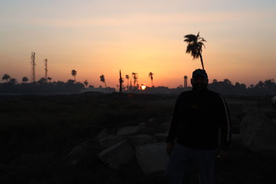 Rear view of silhouette man standing against sky during sunset