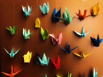 Colorful paper cranes hanging against wall
