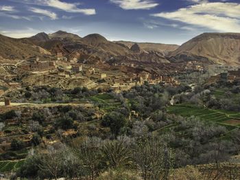 Wide distant view of dades gorge town, morocco countryside. farmland and trees in foreground.
