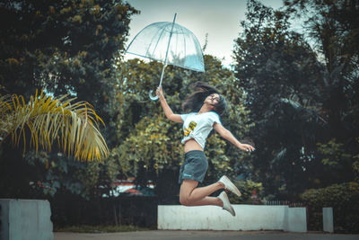 Side view of man jumping against trees