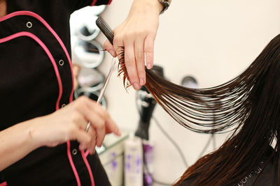 Midsection of hairdresser cutting woman hair