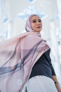 Portrait of young woman standing against blurred background