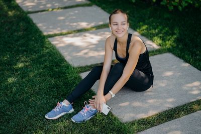 Portrait of smiling woman sitting on footpath