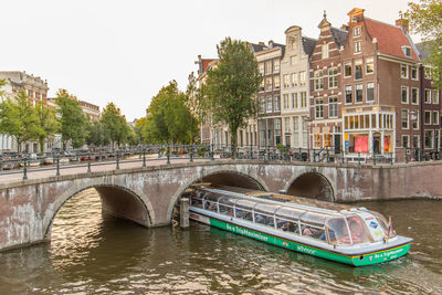 Bridge over river in city against sky