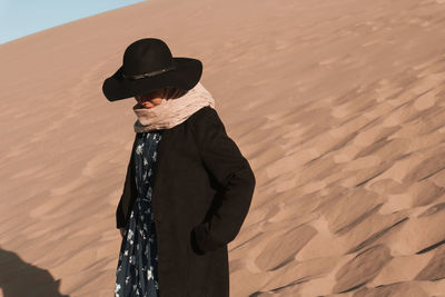 Woman wearing hat standing on sand dunes or desert