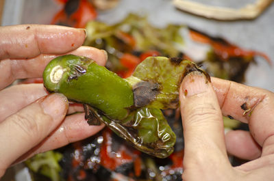 Woman chef cook peeling the skin of a burnt pepper.