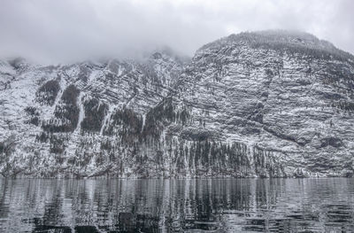 Scenic view of lake by snowcapped mountains against sky