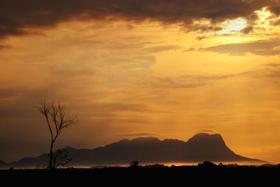 Scenic view of silhouette mountains against orange sky