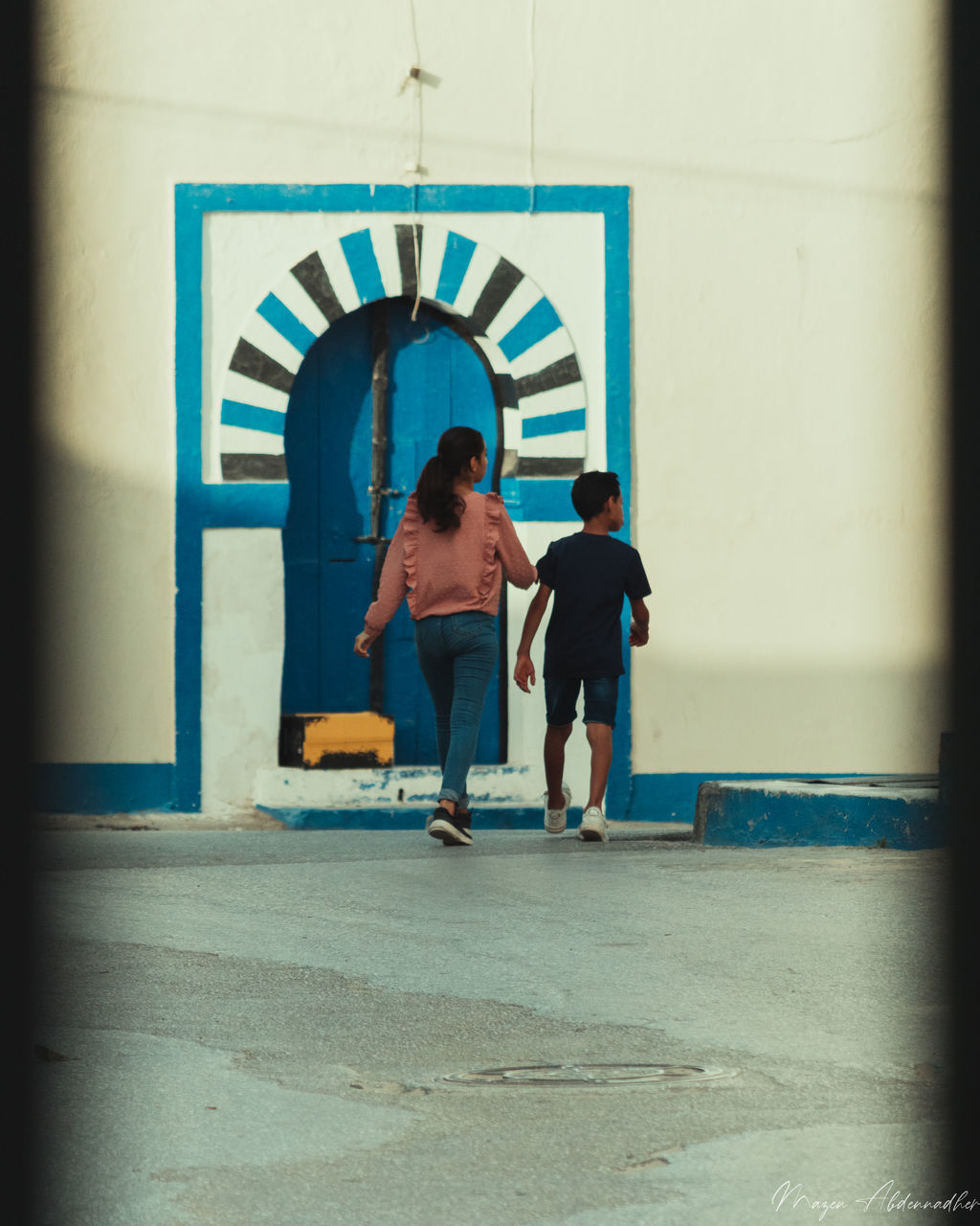 REAR VIEW OF MAN AND WOMAN WALKING ON CORRIDOR