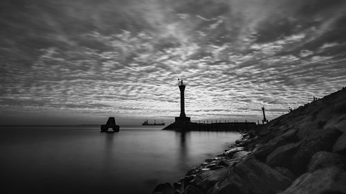 Lighthouse by sea against sky