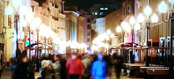 People walking on illuminated street at night