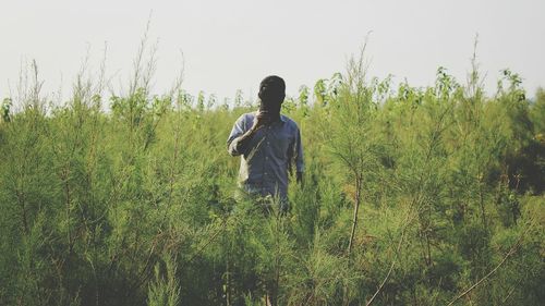 Rear view of man standing on field against clear sky