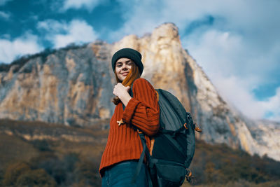 Young woman standing on rock against mountains