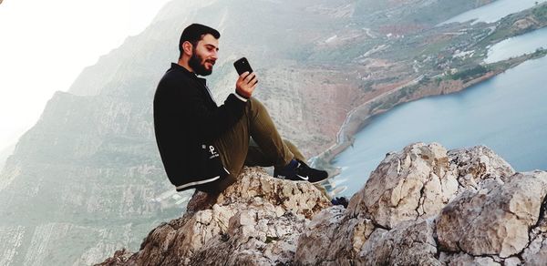 Young man sitting on rock