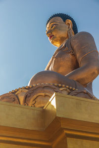 Low angle view of statue against temple building against sky