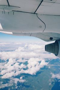 Close-up of airplane flying over landscape against sky