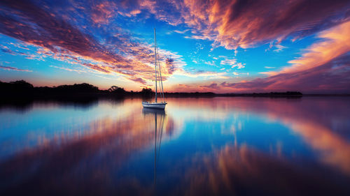 Sailboat on lake against sky during sunset 