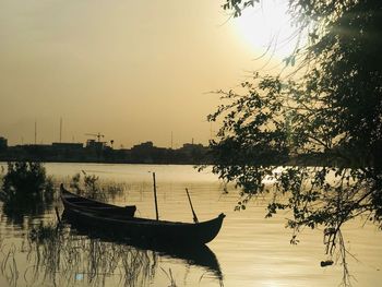 Sailboats moored in lake against sky during sunset