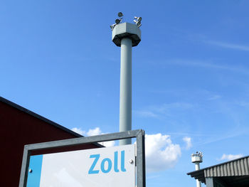 Sign board by communication tower at museum against sky